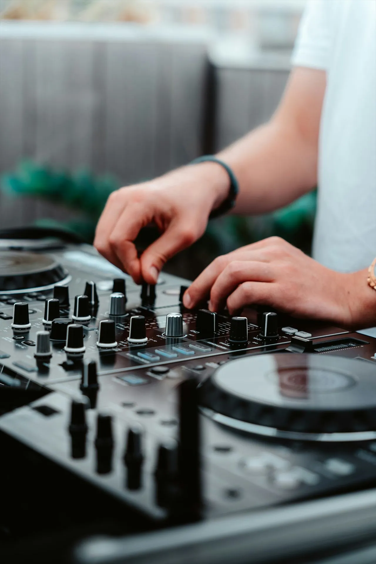Mãos ajustando o mixer de uma controladora durante aula de DJ